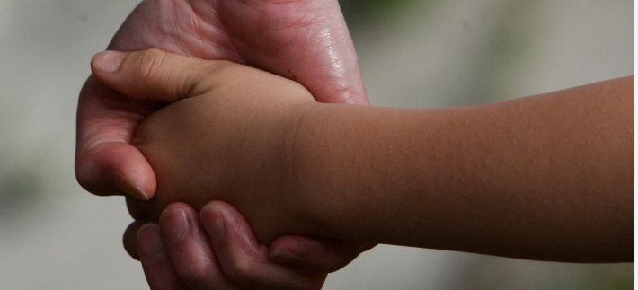 Voksen og barn holder i hånd